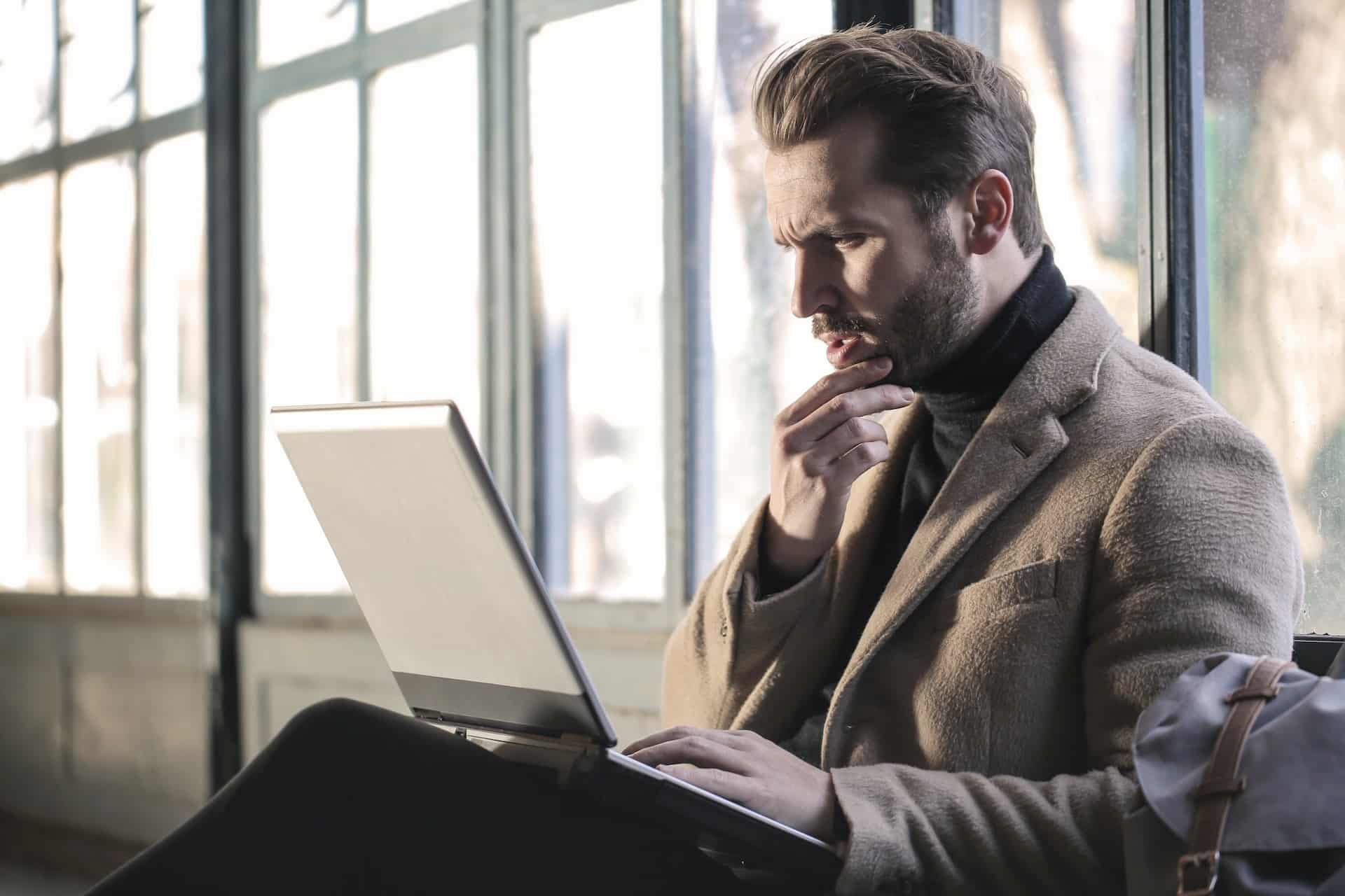 Man holding his chin while facing laptop