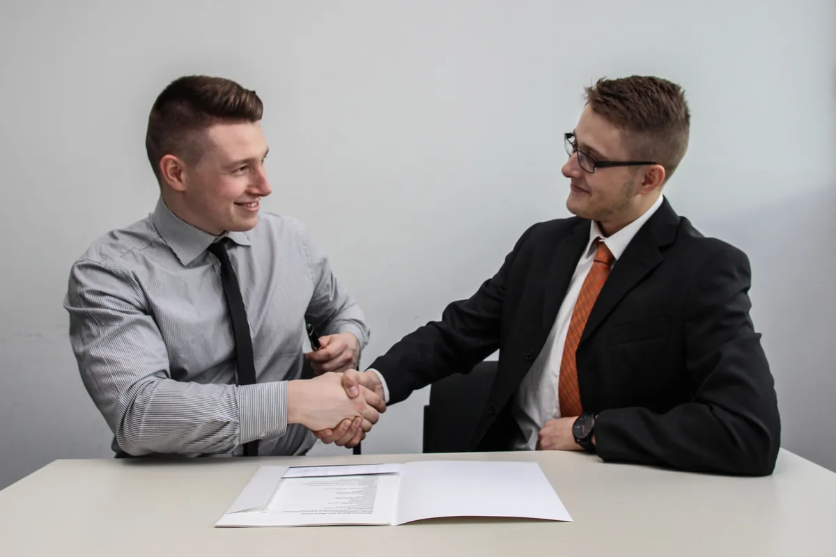 two men facing each other while shake hands