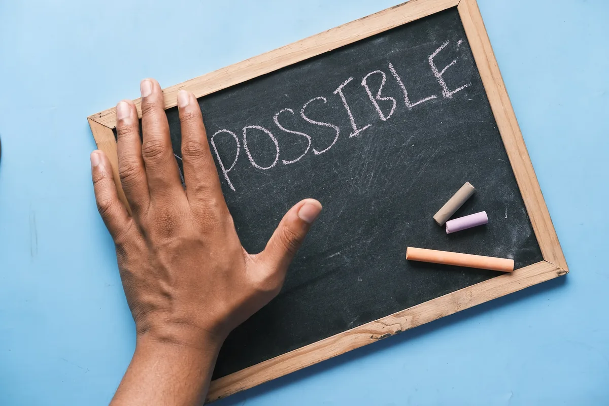 a chalkboard with a hand and written the word possible on it